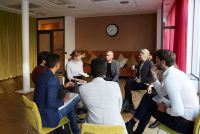 Male and female entrepreneurs discussing while sitting in circle during office workshop