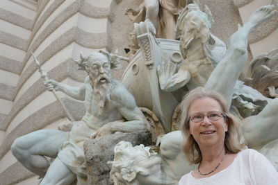 Smiling woman standing against statues at hofburg