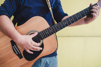 Midsection of man playing guitar