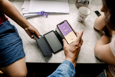 Hand of man holding mobile phone with smart home app over solar panel