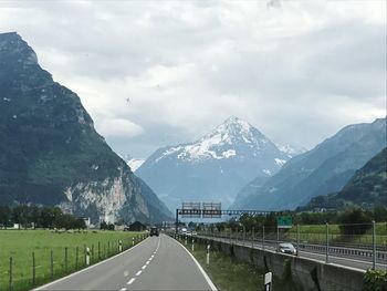 Road leading towards mountains against sky