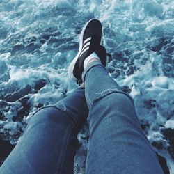 Low section of woman sitting at sea shore