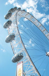 Low angle view of ferris wheel against cloudy sky