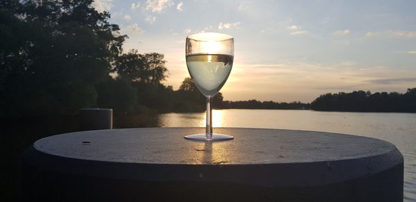 Close-up of wine glass on table against sky during sunset