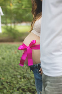 Midsection of woman holding pink umbrella standing outdoors