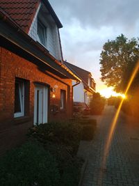 Houses by street against sky during sunset