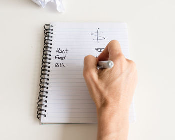 Cropped hand of man writing on book