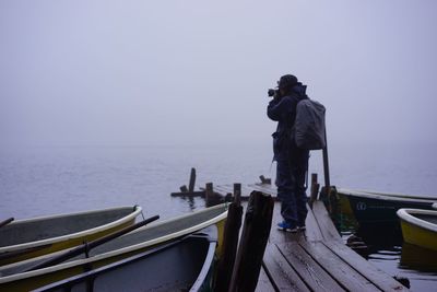 Man standing on jetty in front of sea against clear sky