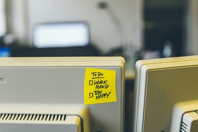 Close-up of adhesive note with text on computer monitor in office