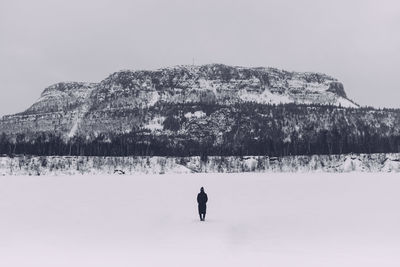 Rear view of woman standing on snow against mountain