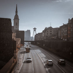 Vehicles on road amidst buildings against sky