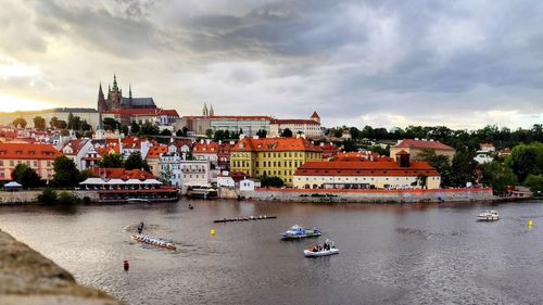 Buildings by river against sky