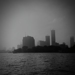 Cityscape by river against sky