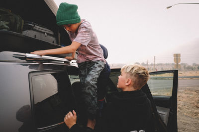Father and son while sitting on car
