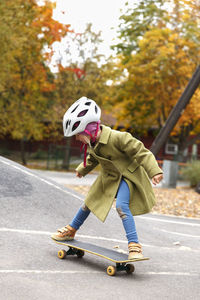 Girl skateboarding at autumn