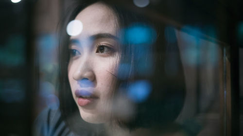 Close-up of woman looking away seen through window