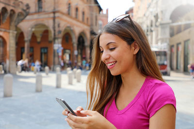 Young woman using mobile phone in city