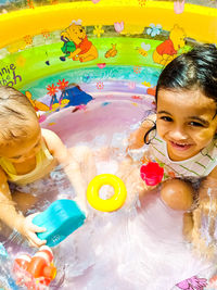 High angle portrait of cute boy with toy floating on water