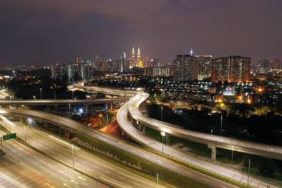 High angle view of light trails on road amidst buildings in city at night