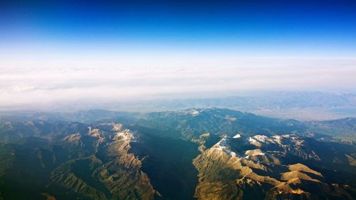 Aerial view of landscape and mountains against blue sky