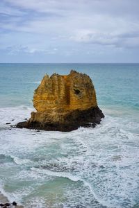 Rock formation on sea shore against sky