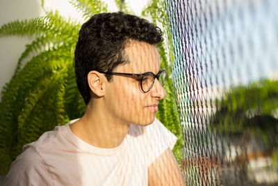 Thoughtful man looking through fence