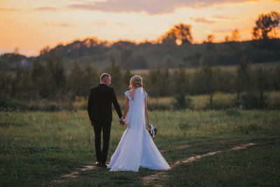 Rear view of mother with daughter in park during sunset