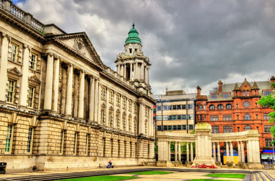Buildings in city against cloudy sky