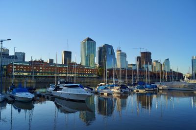 Sailboats moored in harbor against buildings in city