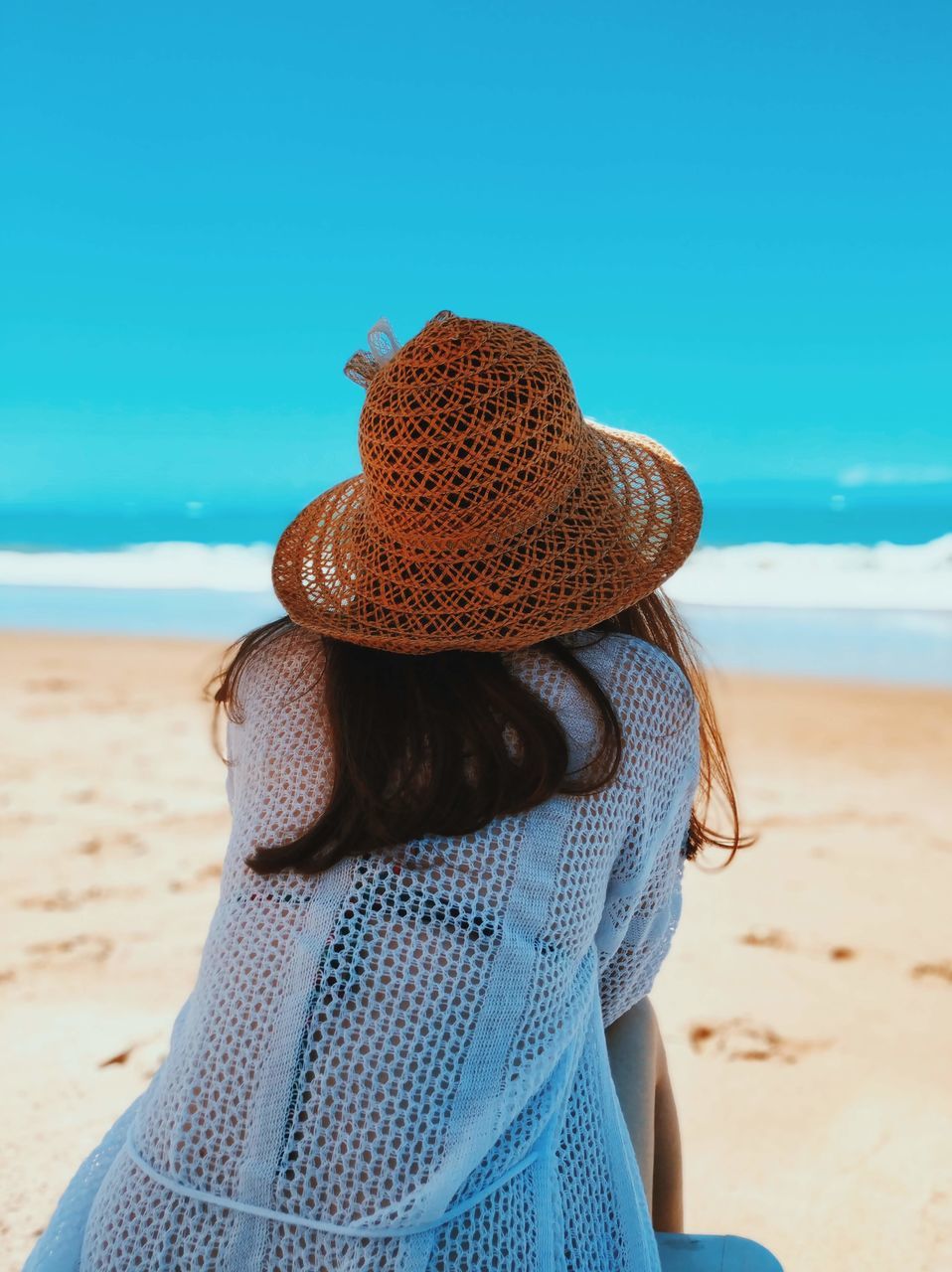 hat, beach, land, clothing, real people, one person, sky, sand, leisure activity, sea, women, lifestyles, water, rear view, adult, day, nature, sun hat, horizon over water, outdoors, hairstyle