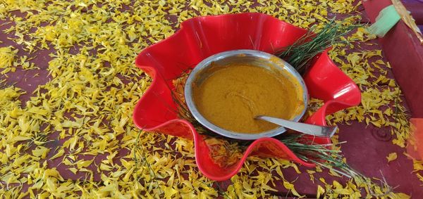 High angle view of turmeric bowl, for haldi function, decorated with flowers petals n grass