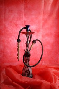 Close-up of hookah on textile against red wall