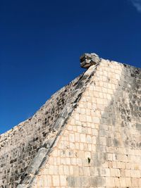 Low angle view of bird perching on stone wall