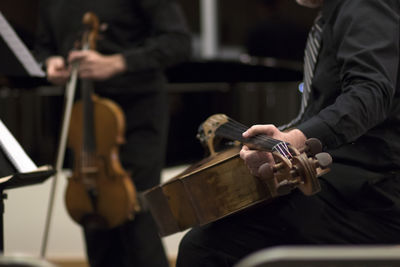 Midsection of men with musical instruments during music concert