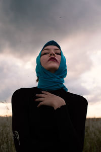 Portrait of beautiful young woman standing against sky