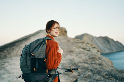 Young woman standing by sea against sky