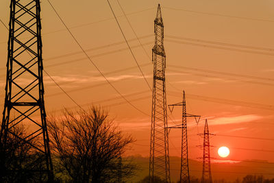 Low angle view of electricity pylon against sky during sunset