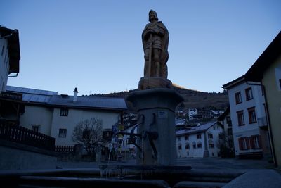 Low angle view of statue against buildings in city against sky