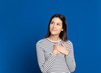 Portrait of young woman against blue background