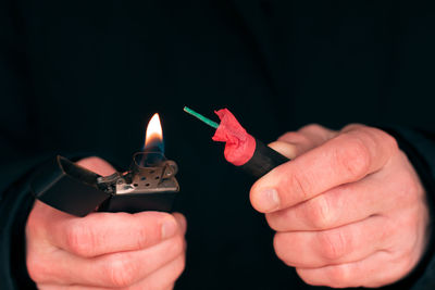 Close-up of hand holding lit candle in the dark