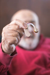 Old man holding hearing aid in hand