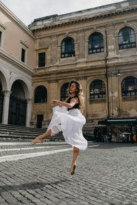 Full length portrait of woman against building in city