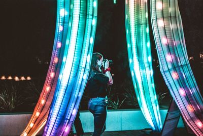 Man standing by illuminated lights at night