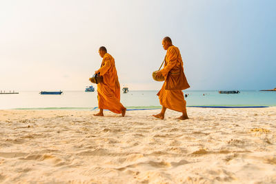 Rear view of people on beach against clear sky