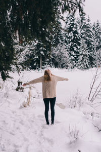 Rear view of woman standing on snow covered field