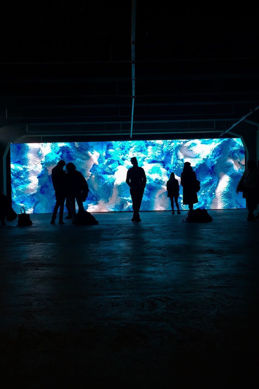 SILHOUETTE PEOPLE WALKING IN ILLUMINATED CORRIDOR OF BUILDING