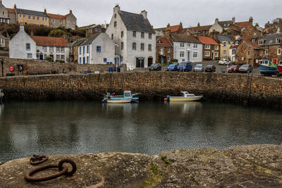 Boats in river by buildings in city