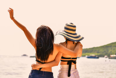 Rear view of woman standing at beach against sky