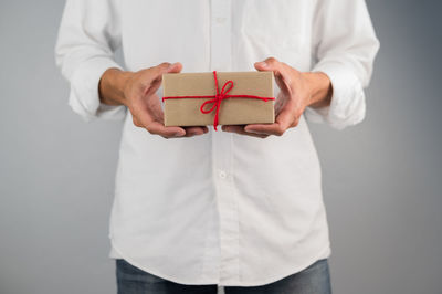 Midsection of man holding paper while standing against white background