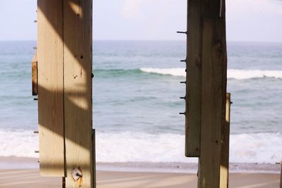 Wooden posts on beach against sky